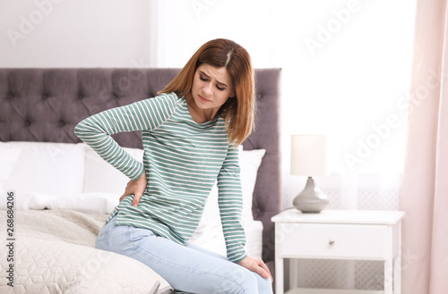 Young woman suffering from back pain at home