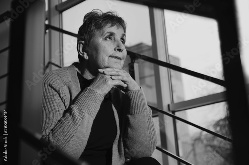Fotografija Poor senior woman sitting on stairs indoors