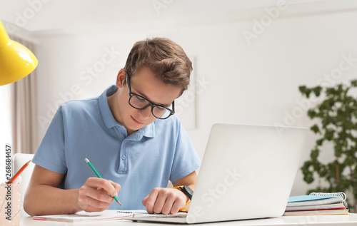 Quadro su tela Teenager boy doing his homework at desk indoors