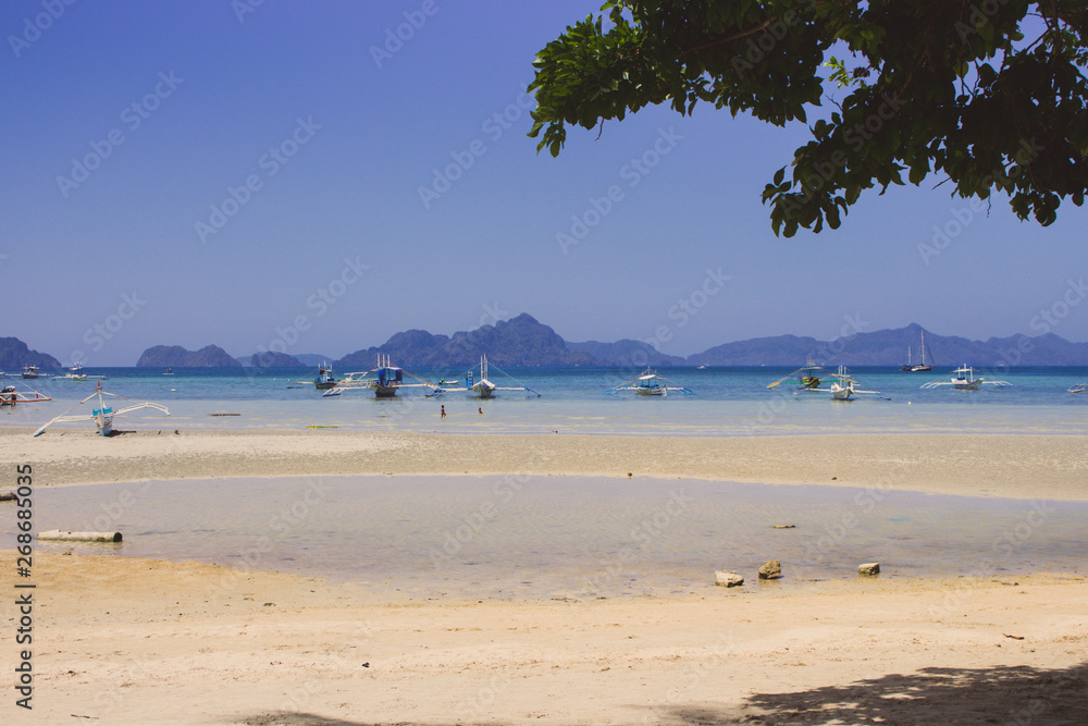 Traditional philippines boats on sea coast in Philippines. Scenic tropical landscape with isles and mountains on horizon. Summer vacation and travel. Idyllic lagoon in Asia. Tropical paradise.