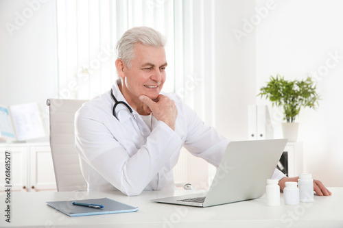 Doctor consulting patient using video chat on laptop in clinic