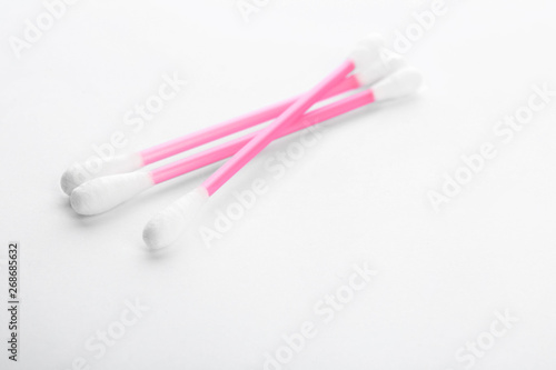 Pink plastic cotton swabs on white background