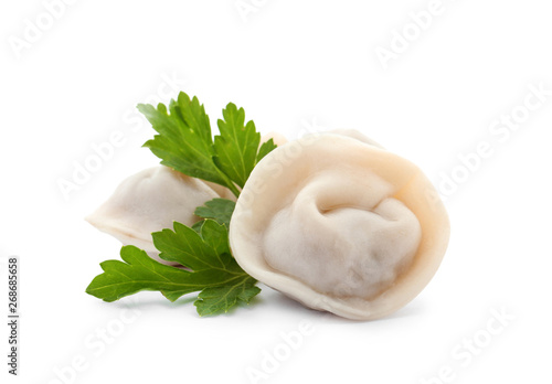 Boiled dumplings and parsley leaves on white background