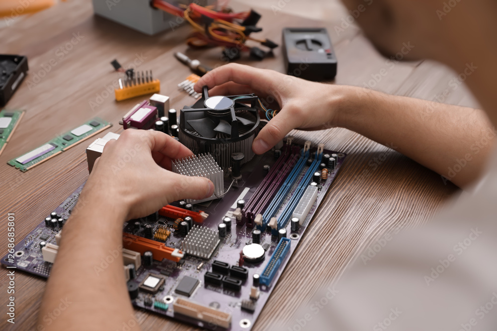 Male technician repairing motherboard at table, closeup Male technician repairing motherboard at table, closeup
