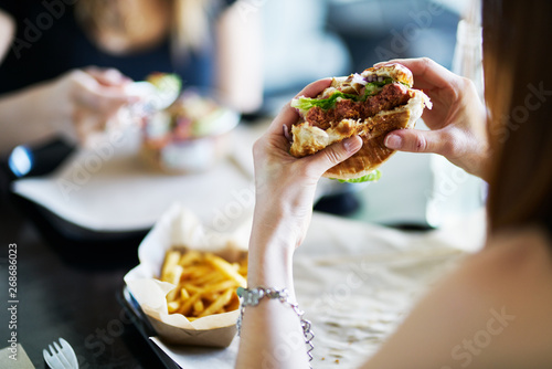 Canvas-taulu woman eating eating vegan meatless burger in restaurant