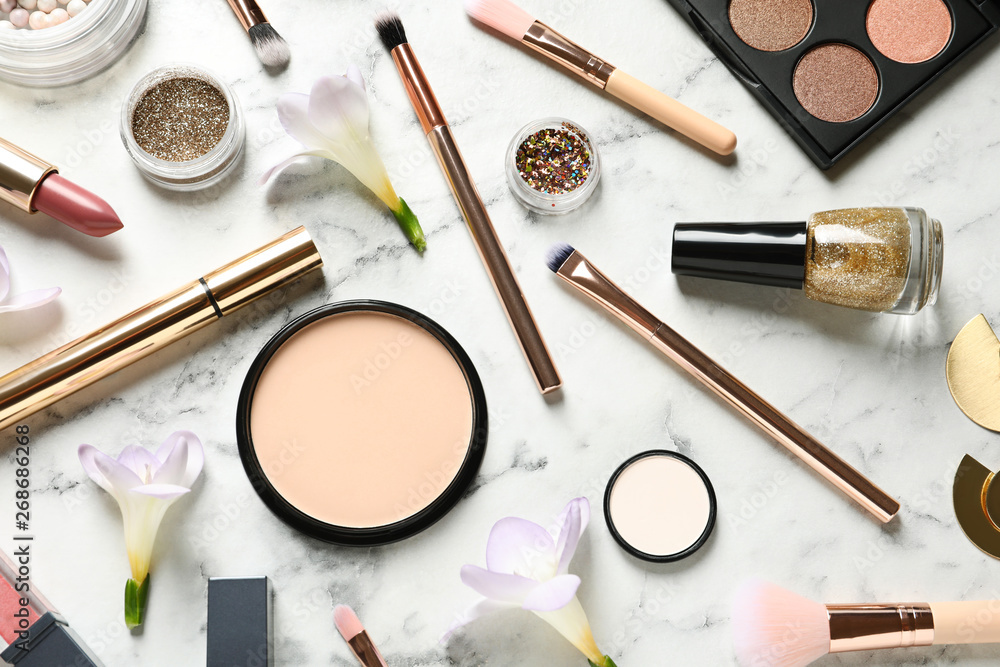Many different makeup products and spring flowers on marble background, flat lay Many different makeup products and spring flowers on marble background, flat lay