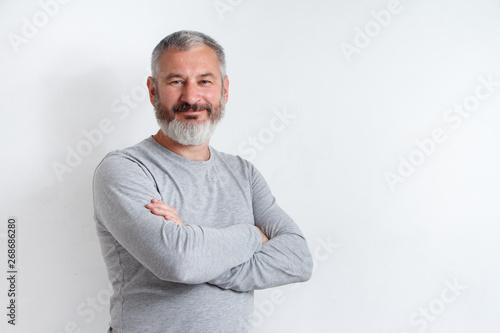 Half-length portrait of a serious gray-haired bearded man in a gray t-shirt on a white background