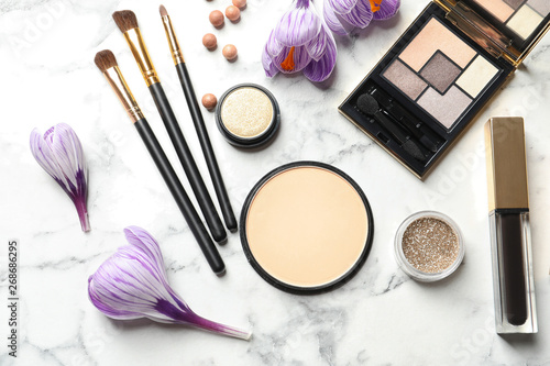 Many different makeup products and spring flowers on marble background, flat lay