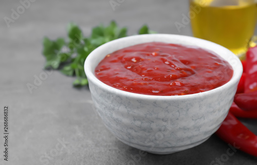 Bowl of hot chili sauce and ingredients on table, closeup. Space for text
