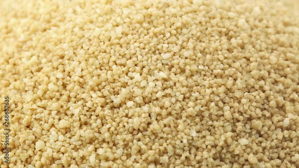 Heap of raw, uncooked couscous rotating close up full frame Heap of raw, uncooked couscous rotating close up full frame