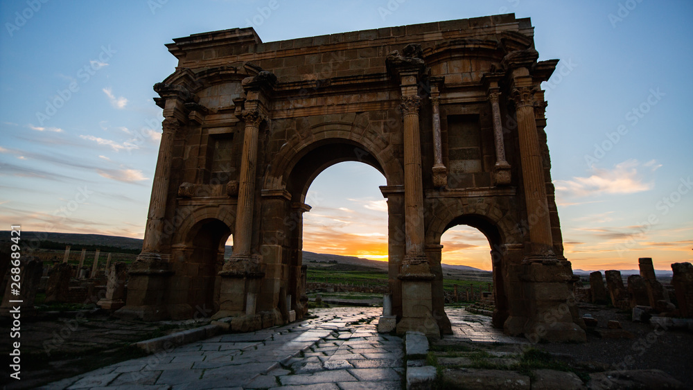 Ancient Roman gate in Roman ruin under sunset