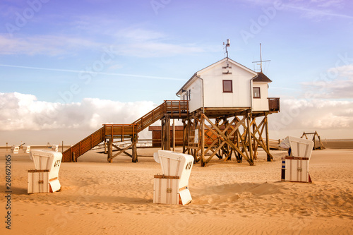 house on wooden stakes on the beach and wicker beach chairs photo