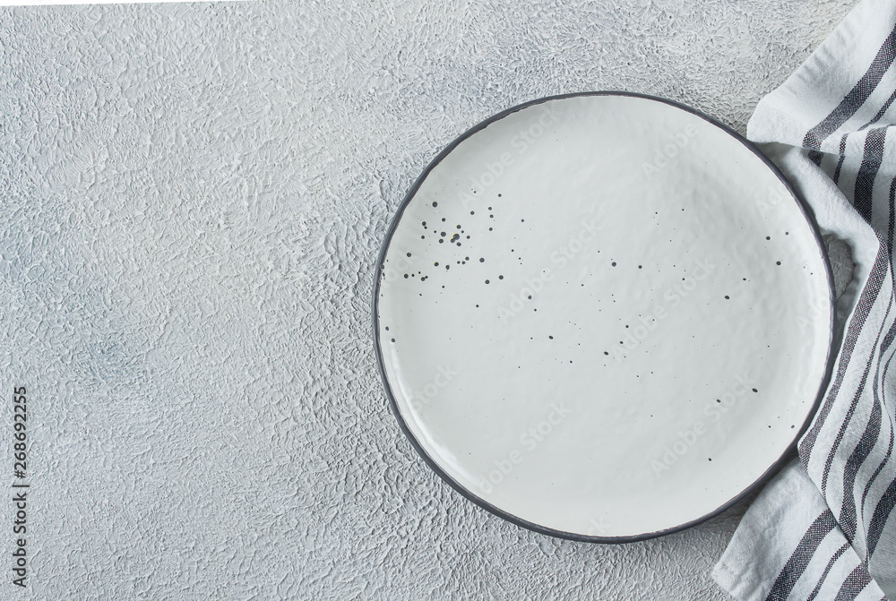 Empty ceramic plate and kitchen striped towel on light stone concrete table background. Copy space. Menu Recipe Concept. Top view. Flat lay Empty ceramic plate and kitchen striped towel on light stone concrete table background. Copy space. Menu Recipe Concept. Top view. Flat lay