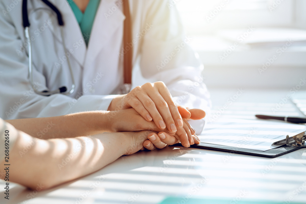 Doctor reassuring patient woman while sitting at the desk in clinic, just hands. Medicine and best service concept Doctor reassuring patient woman while sitting at the desk in clinic, just hands. Medicine and best service concept
