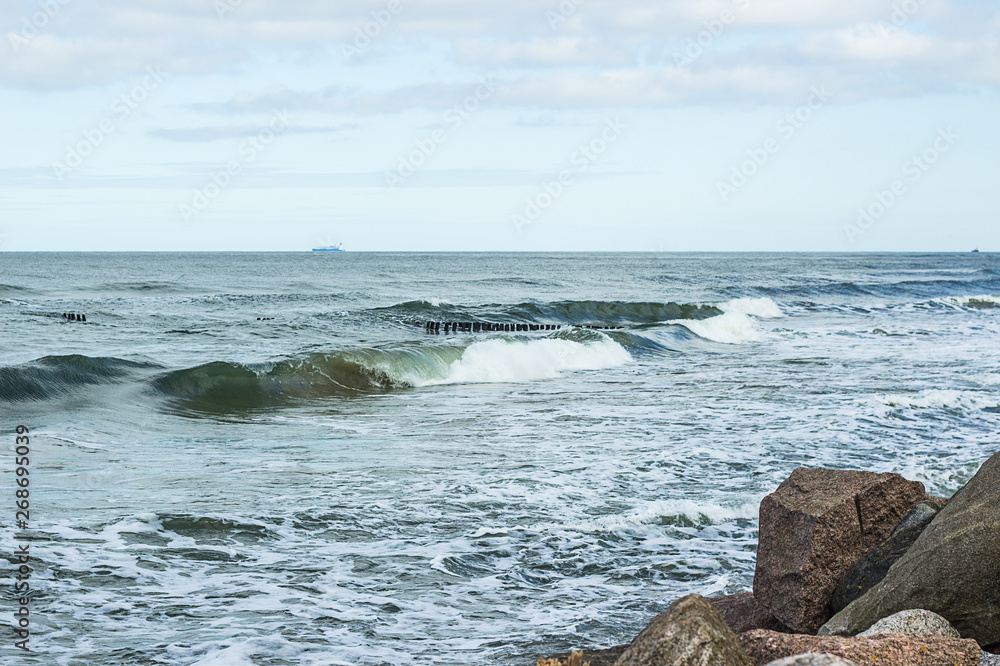 Naklejka premium Empty beach, waves and dramatic sky at the Baltic sea shore line