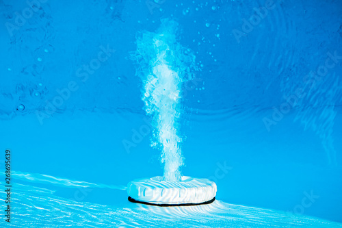 Top view of an active underwater discharge nozzle device equipment set in a blue swimming pool.