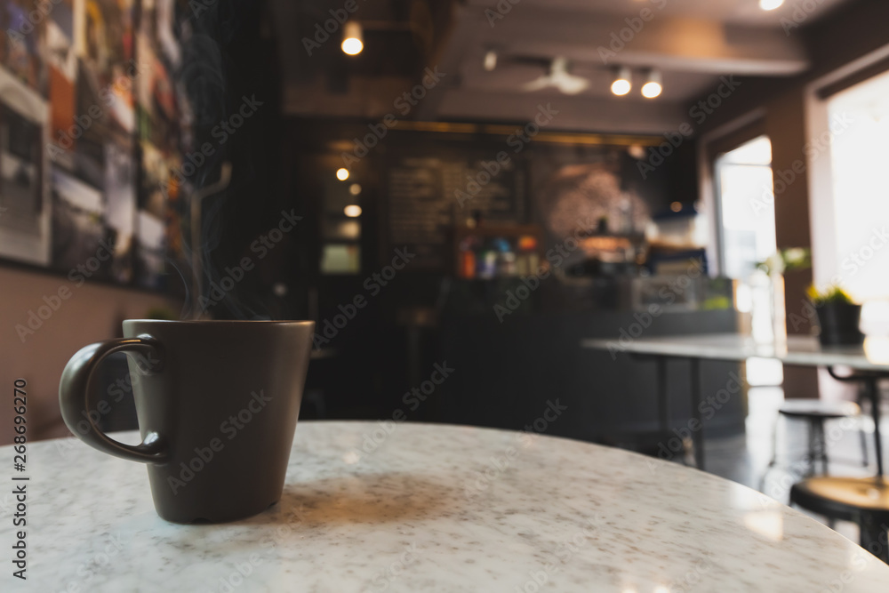 Hot espresso coffee in a black coffee mug on a marble table in a coffee shop