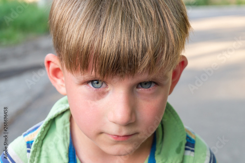 The poor and unhappy boy cries with tears in his eyes and asks for help while looking into the camera.