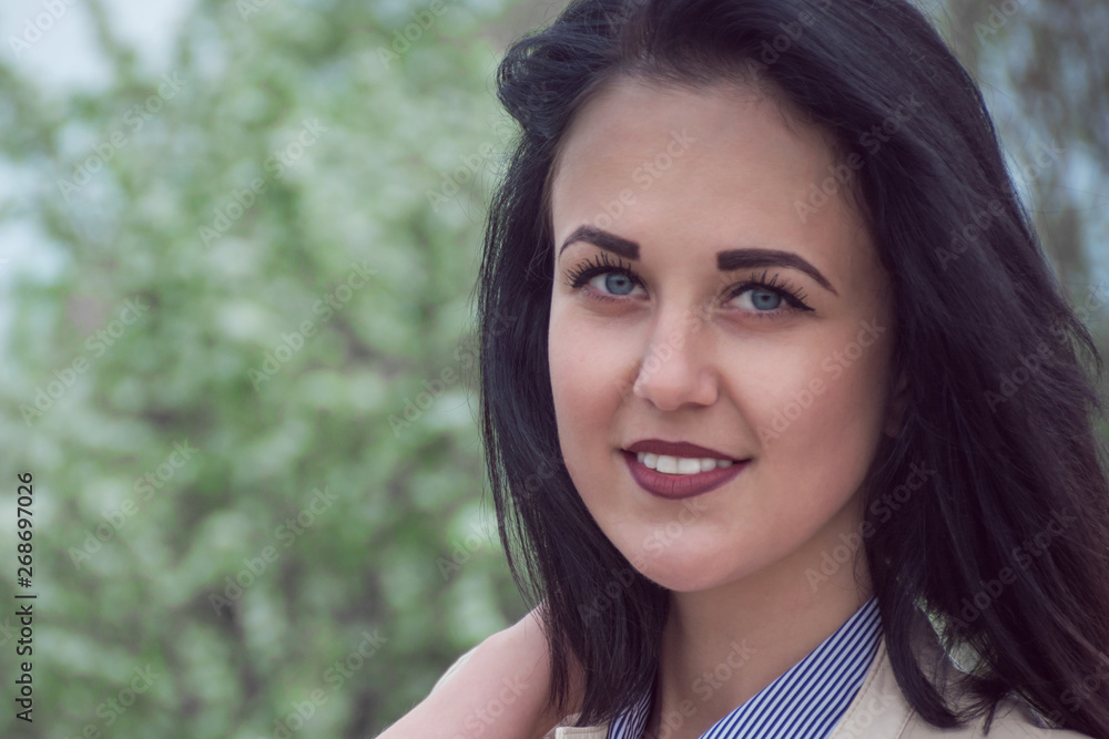 Young woman with perfect skin and white teeth in green foliage in spring. Presenting your product. Expressive facial expressions. Her mouth open with smile Young woman with perfect skin and white teeth in green foliage in spring. Presenting your product. Expressive facial expressions. Her mouth open with smile