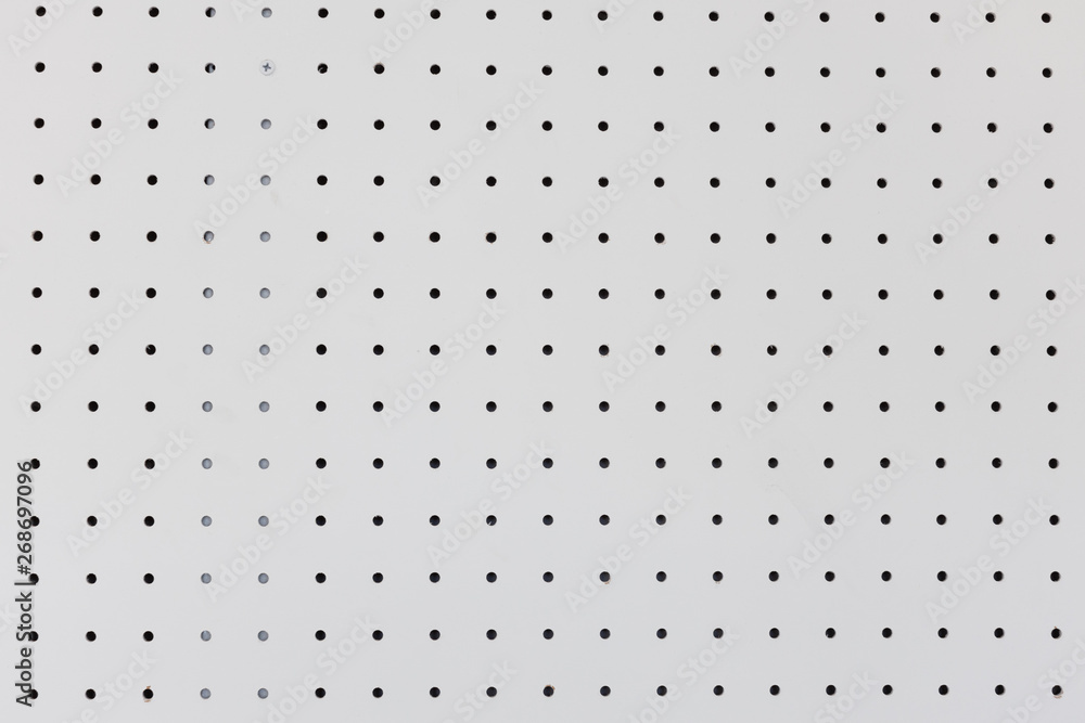 Obraz orderly dot or holes rows and columns on white pegboard wall.