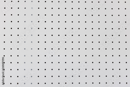 orderly dot or holes rows and columns on white pegboard wall. photo
