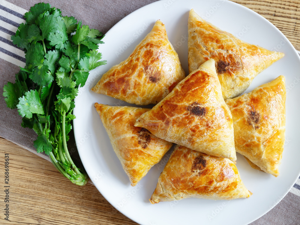 a plate of samsa with fresh cilantro on napkin placed over wooden top a plate of samsa with fresh cilantro on napkin placed over wooden top