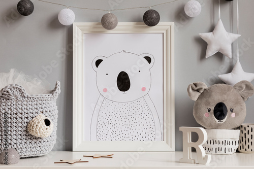 The modern scandinavian newborn baby room with mock up poster frame, koala bear, cotton basket with children accessories. Cozy interior with gray walls. Haniging cotton balls and stars. Template. photo