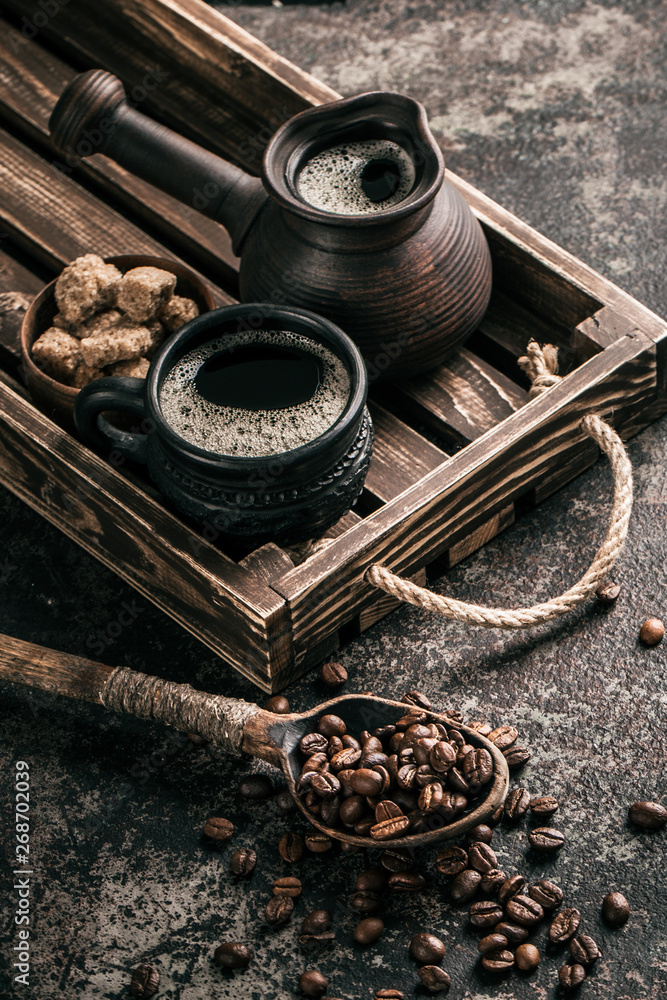 Coffee on wooden tray with coffee beans on dark textured background. Top view with copy space. Background with free text space.