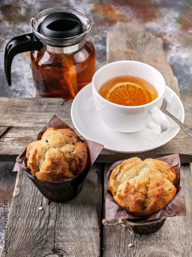 Homemade vanilla Muffins and flavored tea on a rustic wooden background. Close-up. Vertical shot