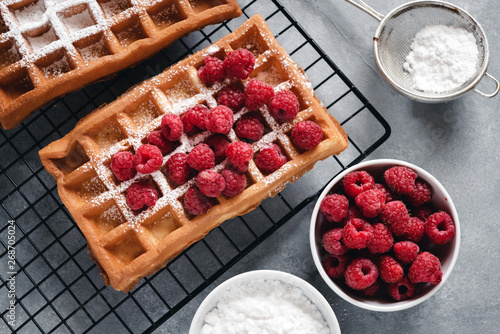 Homemade waffles with raspberries on grey table