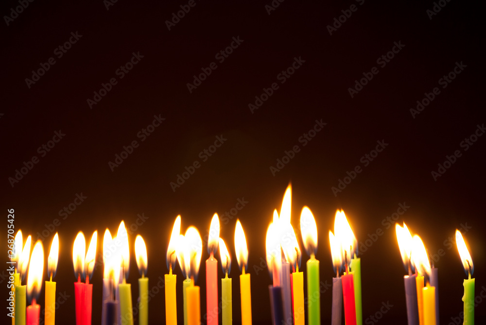 Colorful candles burning in the dark. Flames in darkness. Colorful candles burning in the dark. Flames in darkness.