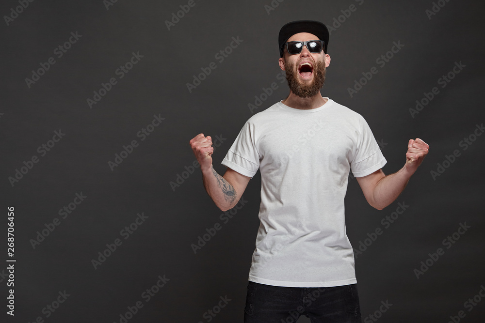 Hipster handsome male model with beard wearing white blank t-shirt and a baseball cap with space for your logo or design in casual urban style Hipster handsome male model with beard wearing white blank t-shirt and a baseball cap with space for your logo or design in casual urban style