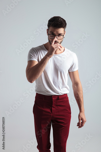 Determined man walking forward and adjusting his glasses
