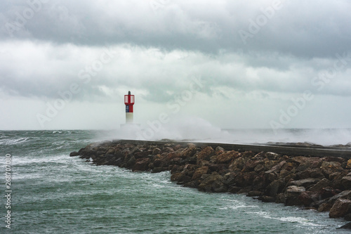des vagues submergent un quai et son phare   photo