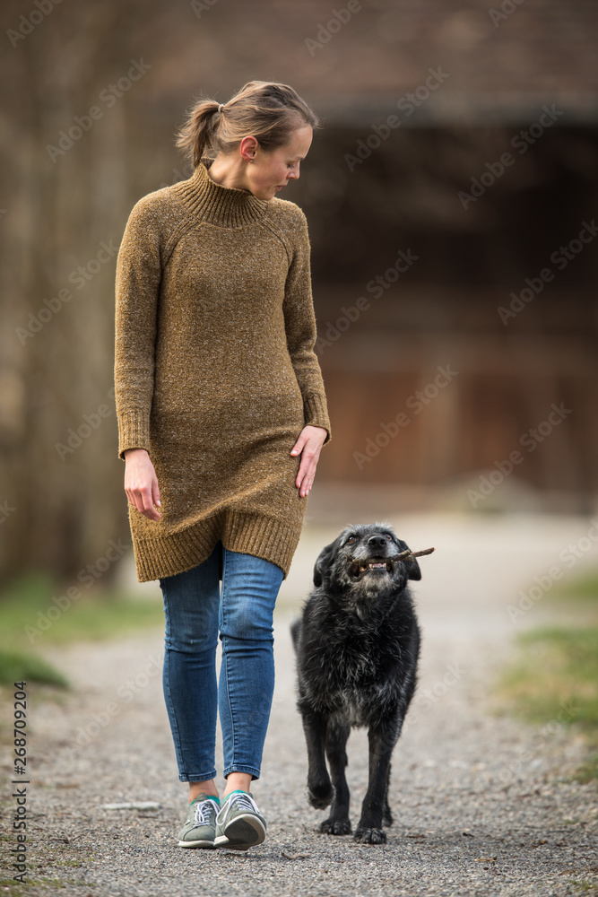 Young woman walking her dog after work in a park Young woman walking her dog after work in a park