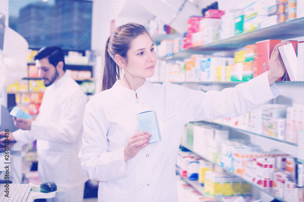 Glad female looking medicines near shelves