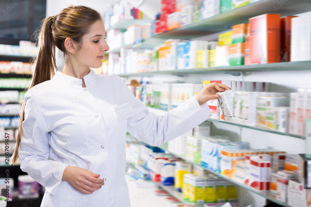 Female specialist looking medicines near shelves