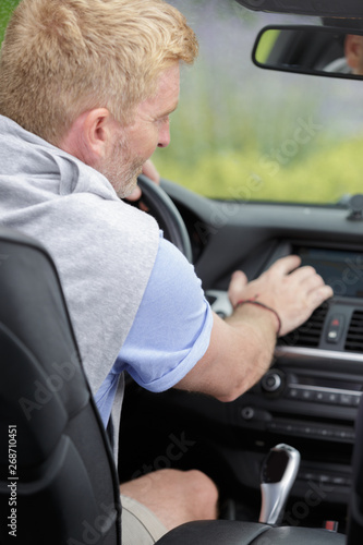 man driving car and turning switch on dashboard