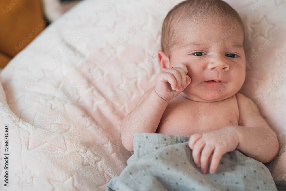 Cute adorable newborn baby in white and blue bed and wrapped in blanket. New born child, little