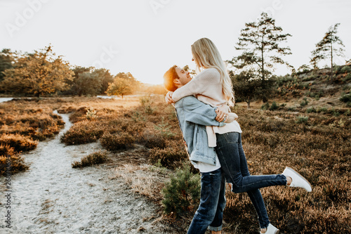 Verliebter Mann umarmt junge Frau, haben Spaß und sind glücklich in der Natur bei Sonnenuntergang
