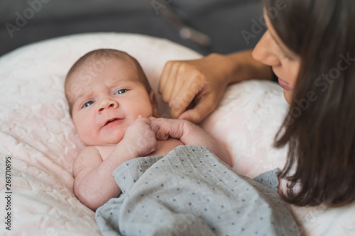 Happy mother giving cuddles and playing smiling with her cute newborn. Family, new life, childhood, beginning concept.