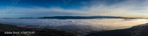 Obraz na płótnie Landscape with inverse cloudiness and protruding peaks of mountains during sunrise