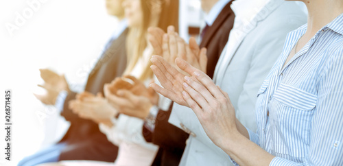 Business people clapping and applause at meeting or conference, close-up of hands. Group of unknown businessmen and women in modern white office. Success teamwork or corporate coaching concept © rogerphoto