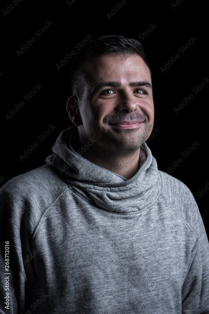 Fototapeta premium Studio portrait of a smiling man looking at the camera. Isolated on black background. Vertical.