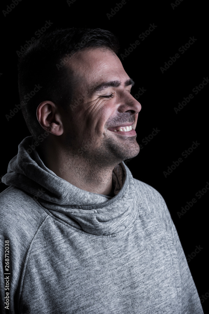 Side studio portrait of a smiling man with closed eyes. Isolated on black background. Vertical. Side studio portrait of a smiling man with closed eyes. Isolated on black background. Vertical.