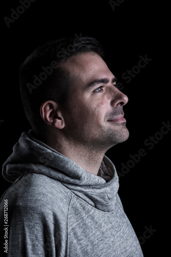 Side studio portrait of a man looking up. Isolated on black background. Vertical.