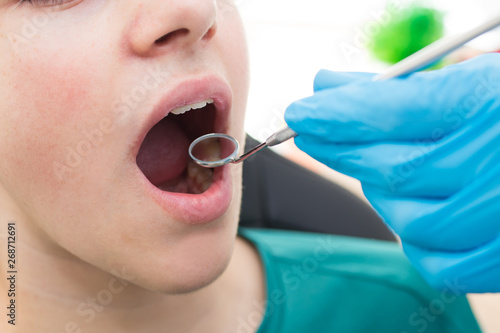 dentist working in the mouth of the child or teenager photo