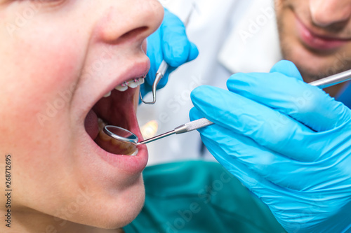 dentist working in the mouth of the child or teenager