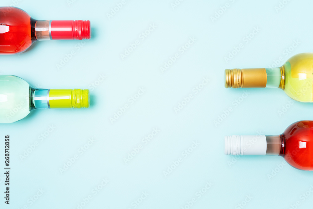 Screw bottle foil caps in different bright colors of white and rose wine bottles on blue background with copy space. Minimal abstract colorful mockup concept of alcohol beverage. Flat lay. Screw bottle foil caps in different bright colors of white and rose wine bottles on blue background with copy space. Minimal abstract colorful mockup concept of alcohol beverage. Flat lay.