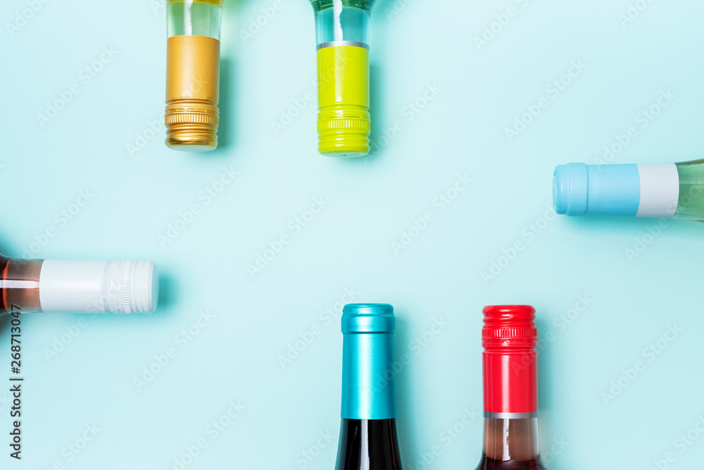 Screw bottle foil caps in different bright colors of white and rose wine bottles on blue background with copy space. Minimal abstract colorful mockup concept of alcohol beverage. Flat lay. Screw bottle foil caps in different bright colors of white and rose wine bottles on blue background with copy space. Minimal abstract colorful mockup concept of alcohol beverage. Flat lay.